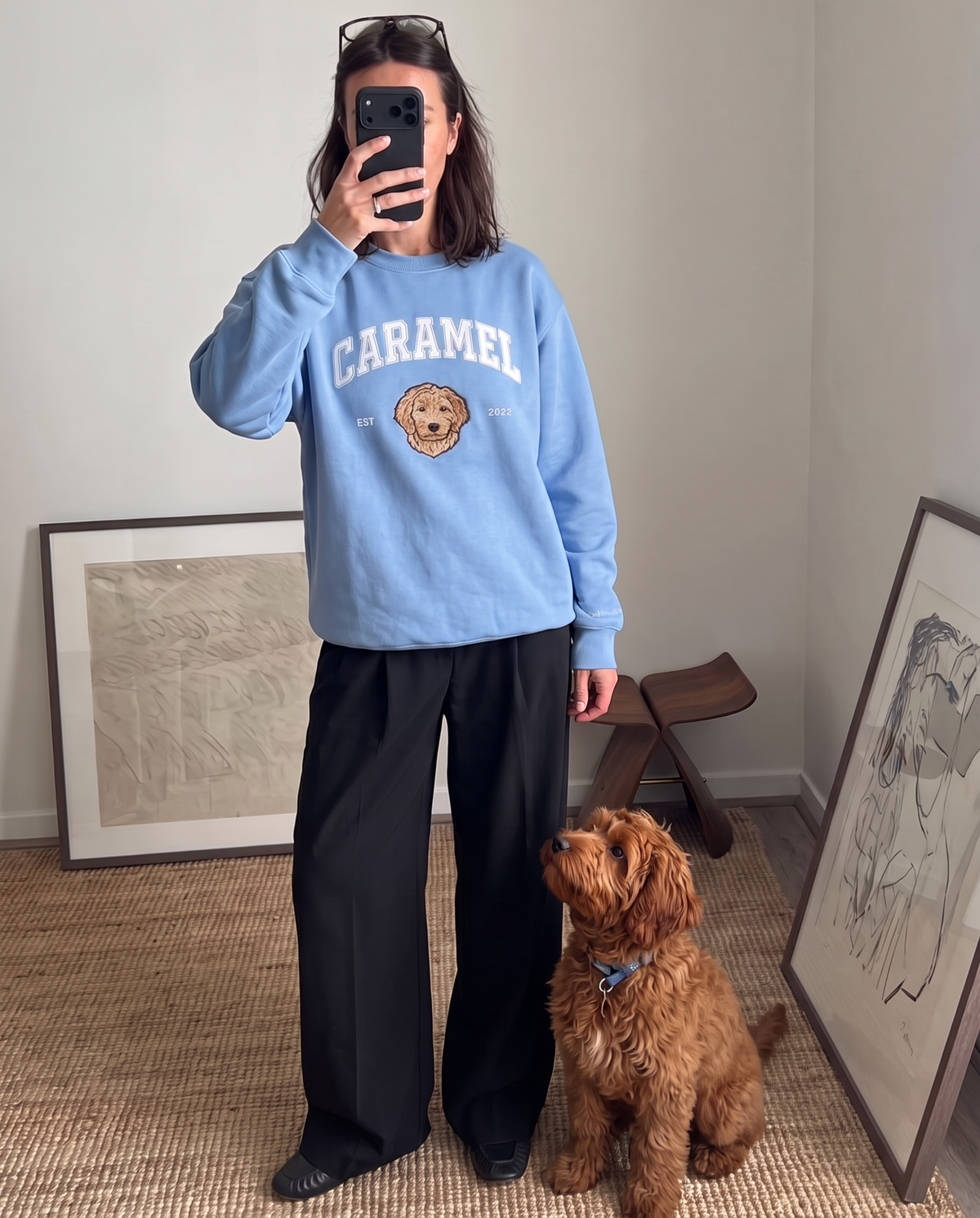 Customer in the light blue University sweatshirt beside the goldendoodle embroidered on it