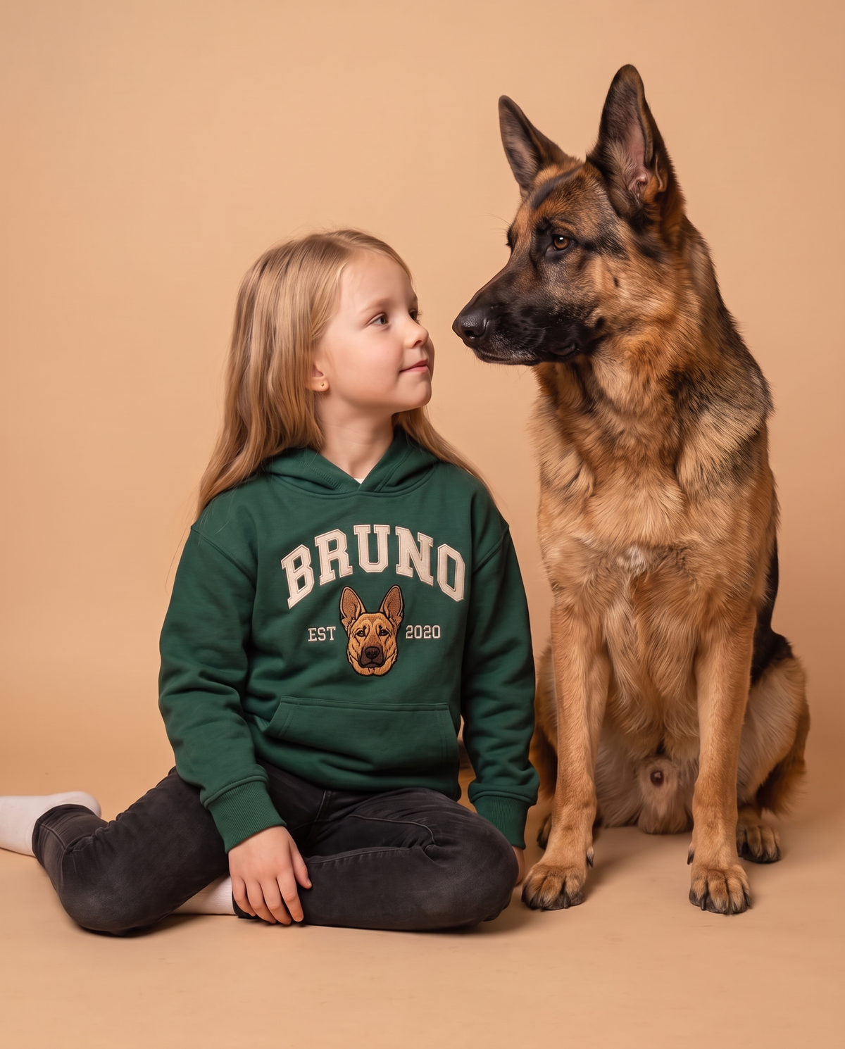 Girl in a green kids University hoodie beside the german shepherd embroidered on it